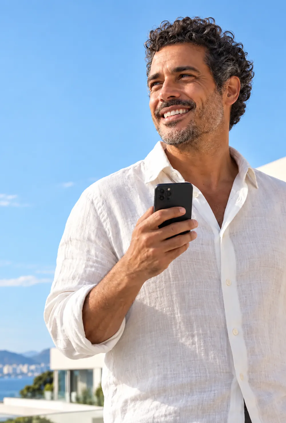 Pedro, personagem ilustrativo, sorri ao ar livre com uma camisa de linho branca e um celular preto na mão.